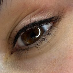 SALON KOSMETYCZNY PIN-UP Monika Adamczyk - Makro zbliżenie na oko z precyzyjną kreską eyelinerem, podkreślone brązowe tęczówki i długie rzęsy. Delikatny makijaż oka.