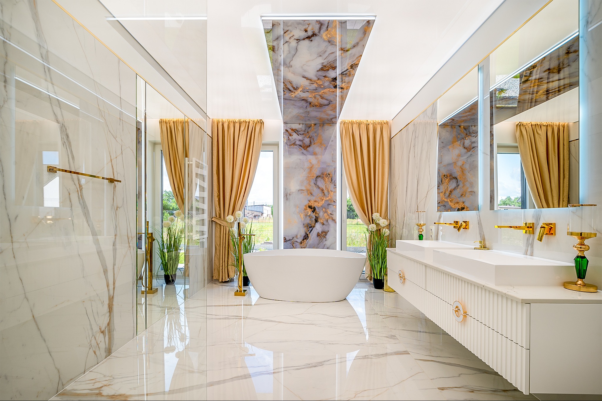 Luksusowa łazienka z marmurowymi ścianami i podłogą, wolnostojącą wanną, złotą armaturą i zasłonami. Nowoczesny design z elementami glamour.