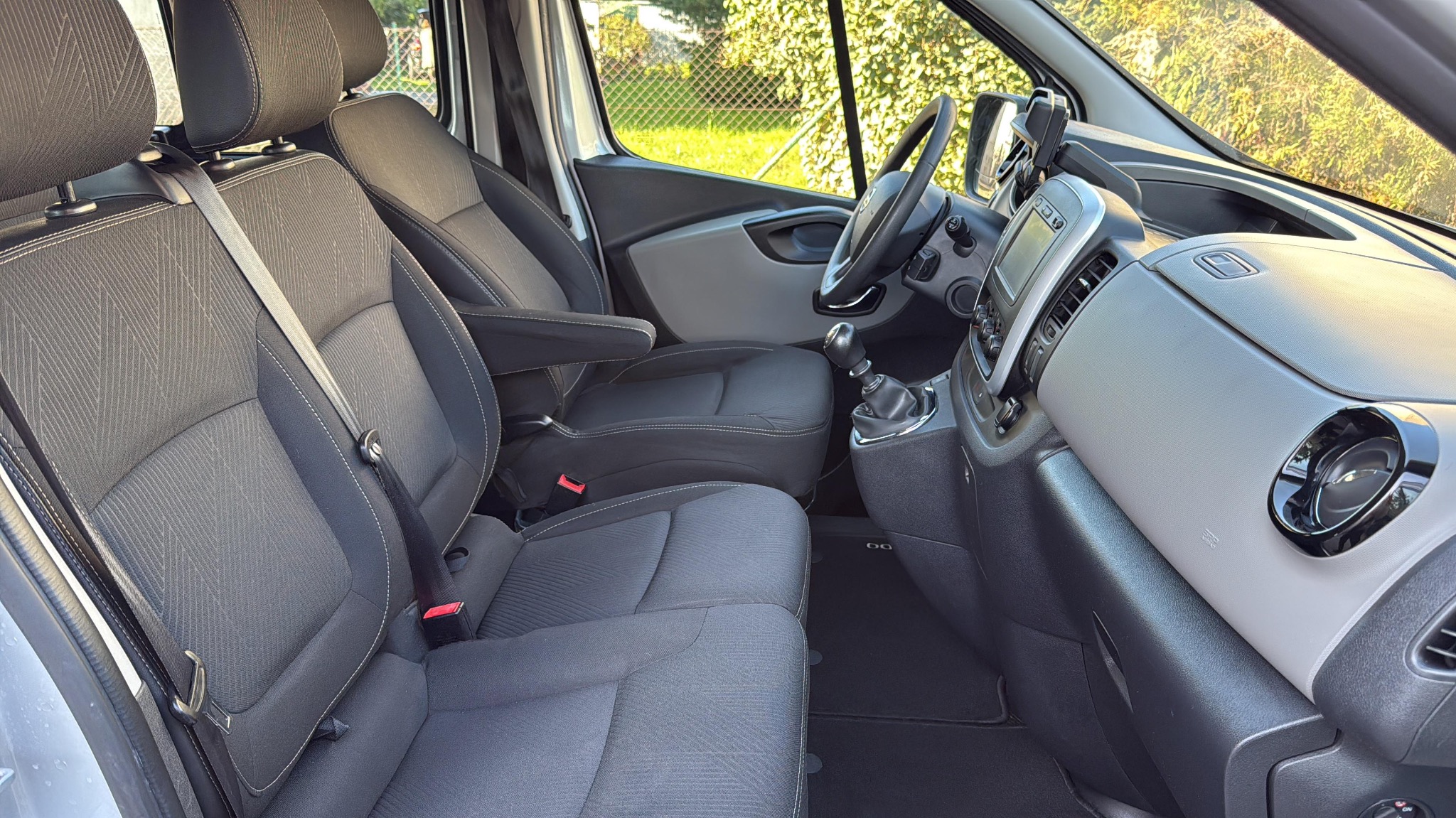 Wnętrze busa z widocznymi fotelami kierowcy i pasażera, deską rozdzielczą oraz elementami wyposażenia. Czyste i zadbane wnętrze pojazdu.