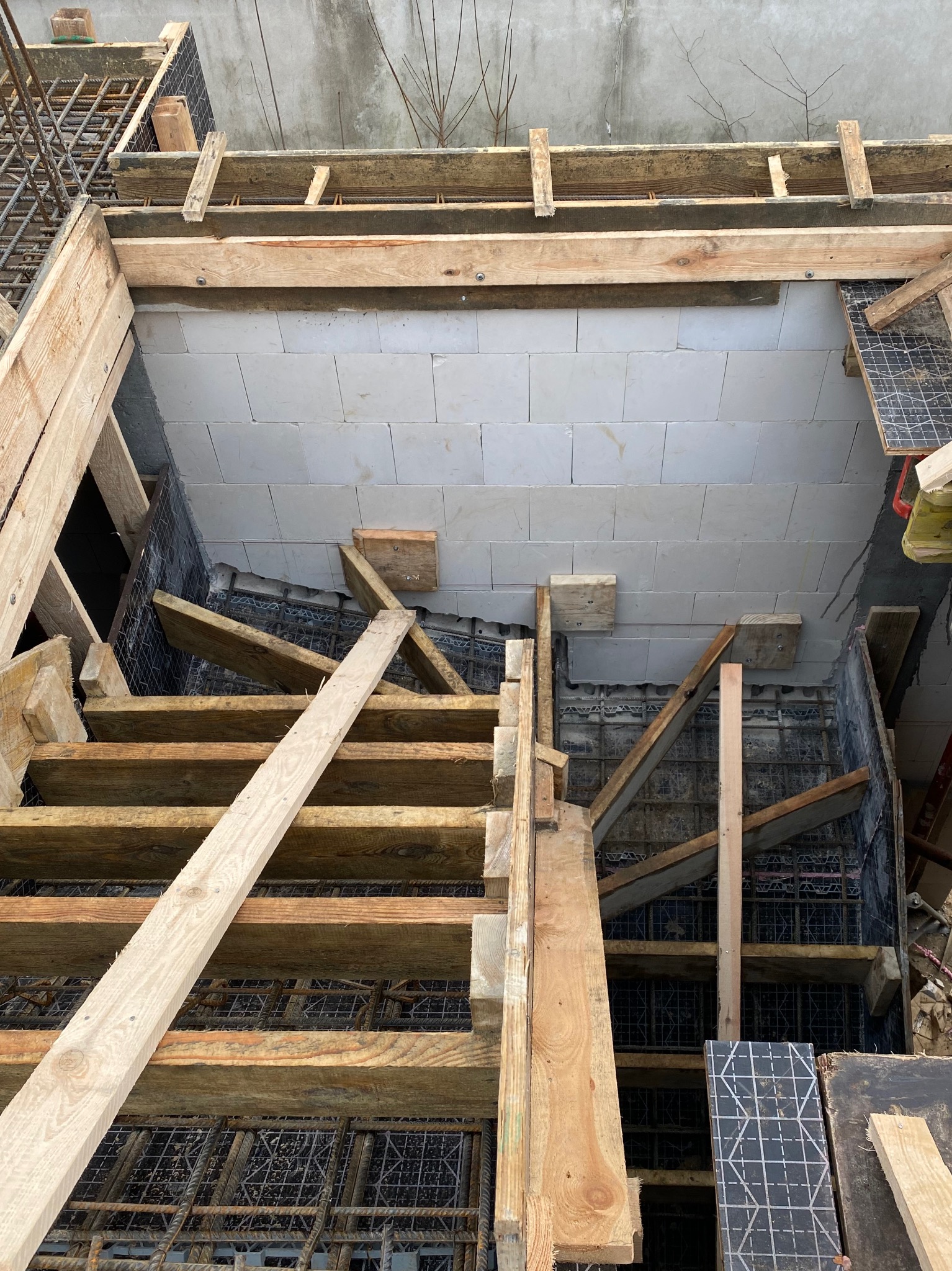 Budowa schodów żelbetowych z drewnianym szalunkiem i zbrojeniem, widok z góry. Prace zbrojarskie w Tuchowicz.