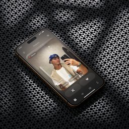 zevyservices Krystian Dylewski - Smartfon z otwartą aplikacją randkową, wyświetlający profil młodego mężczyzny robiącego selfie w lustrze, na tle czarnej, perforowanej powierzchni.