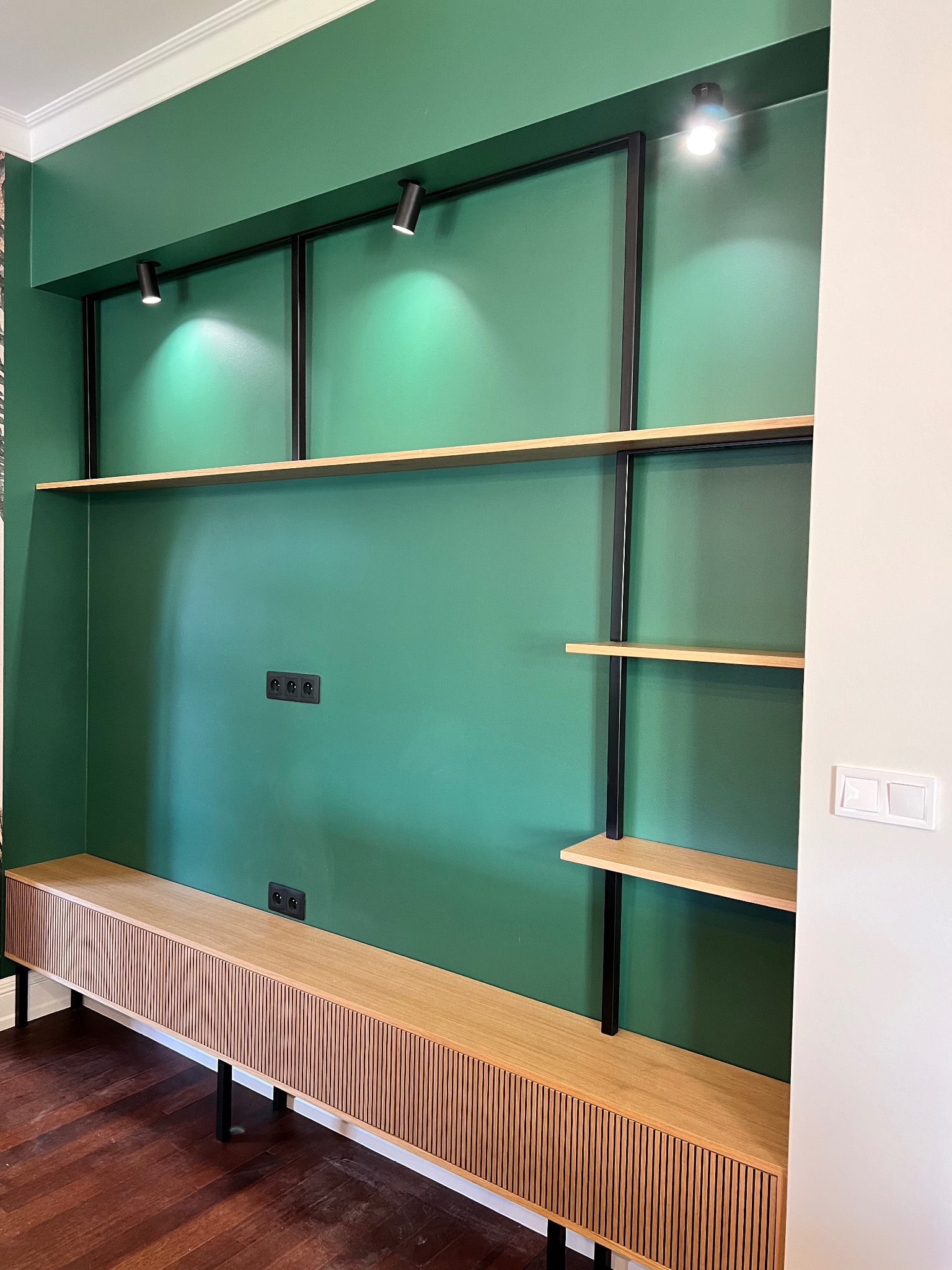 Nowoczesna zabudowa meblowa z ryflowanym frontem i półkami na metalowym stelażu, na tle zielonej ściany. Realizacja z Wrocławia.