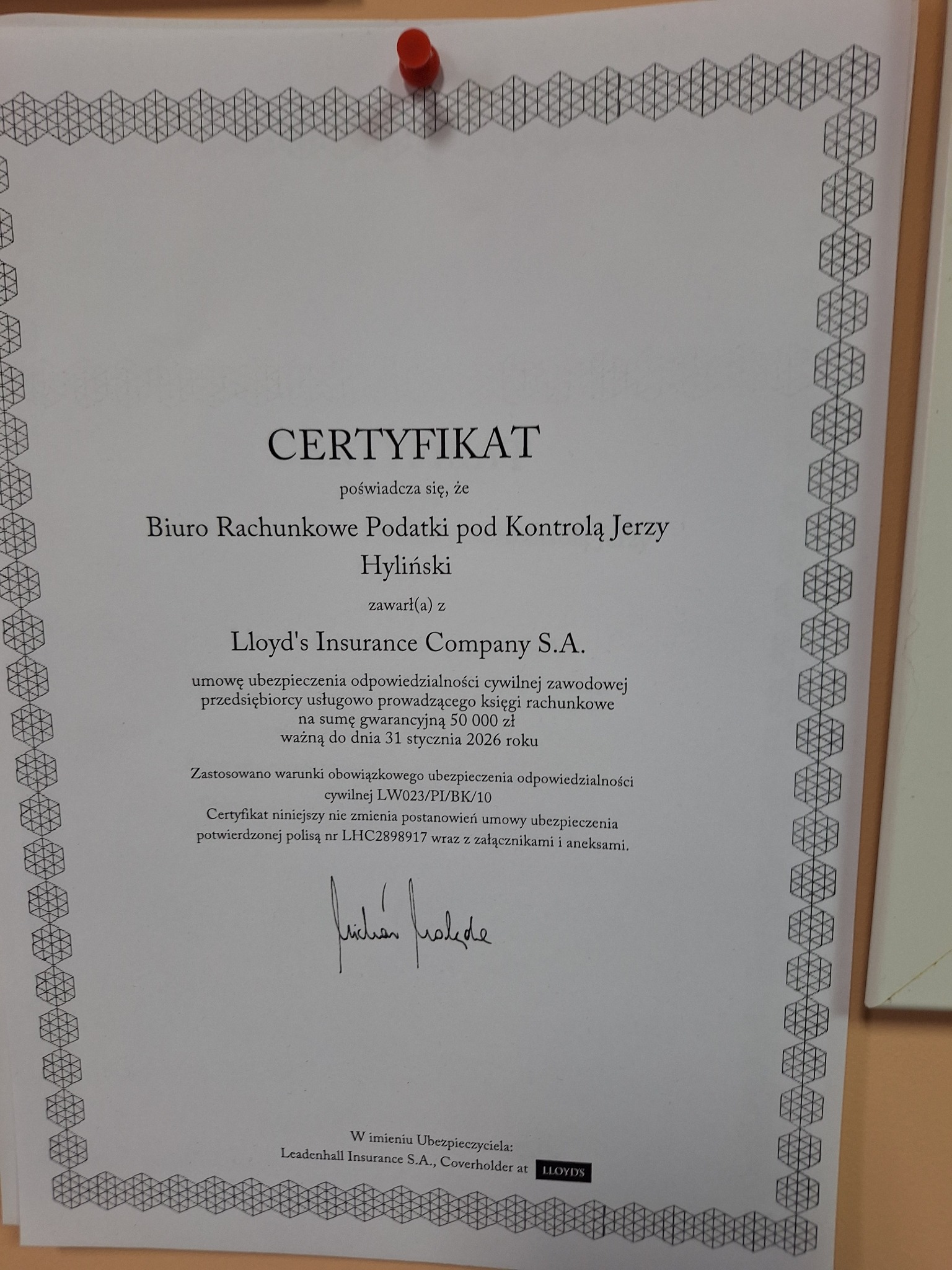 Certyfikat ubezpieczenia OC biura rachunkowego 'Biuro Rachunkowe Podatki pod Kontrolą Jerzy Hyliński' z Lloyd's Insurance Company S.A., przypięty pinezką.