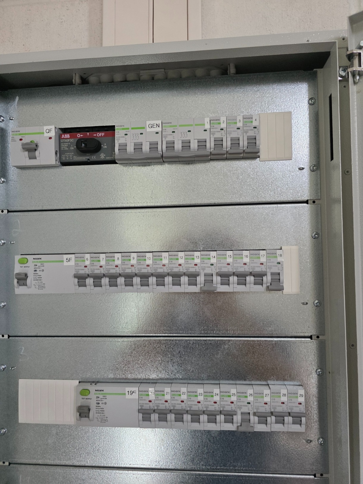 Rozdzielnica elektryczna z bezpiecznikami NOARK, widok z bliska. Instalacja elektryczna w nowym budownictwie we Wrocławiu. Szyna DIN i moduły zabezpieczeń.