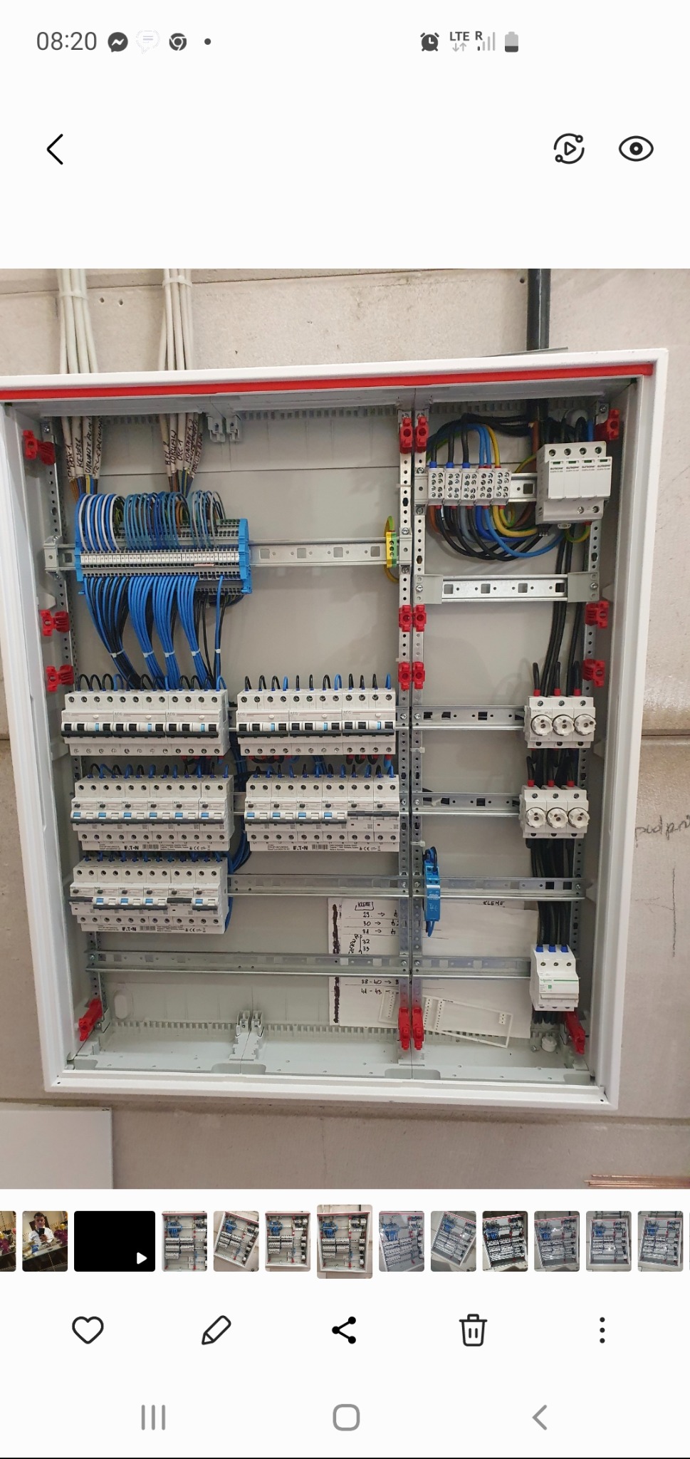 Rozdzielnica elektryczna w białej obudowie z czerwonymi akcentami, widoczne liczne kable, bezpieczniki i elementy montażowe. Instalacja po zakończonym montażu.