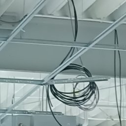 Usługi Transportowe - Instalacja elektryczna: przewody ułożone pod sufitem podwieszanym, widoczne elementy konstrukcji. Ujęcie z dołu, sufit w trakcie montażu.