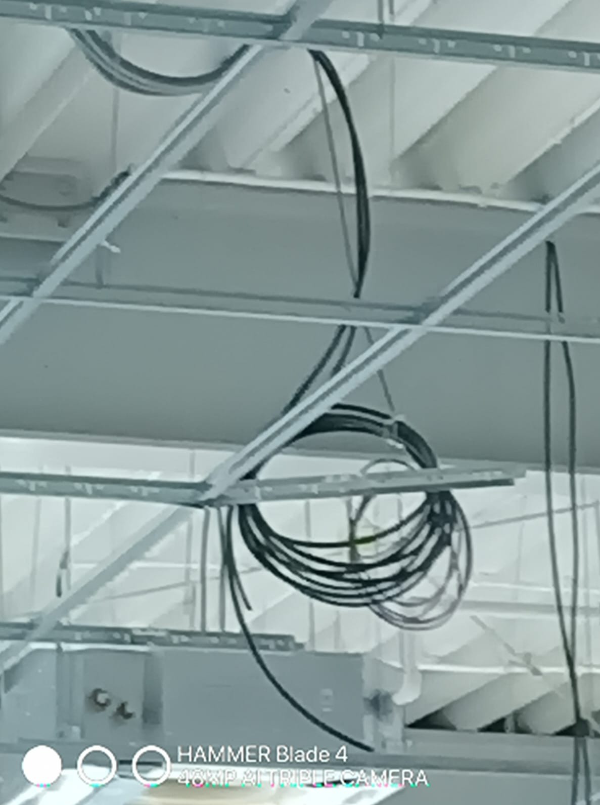 Instalacja elektryczna: przewody ułożone pod sufitem podwieszanym, widoczne elementy konstrukcji. Ujęcie z dołu, sufit w trakcie montażu.