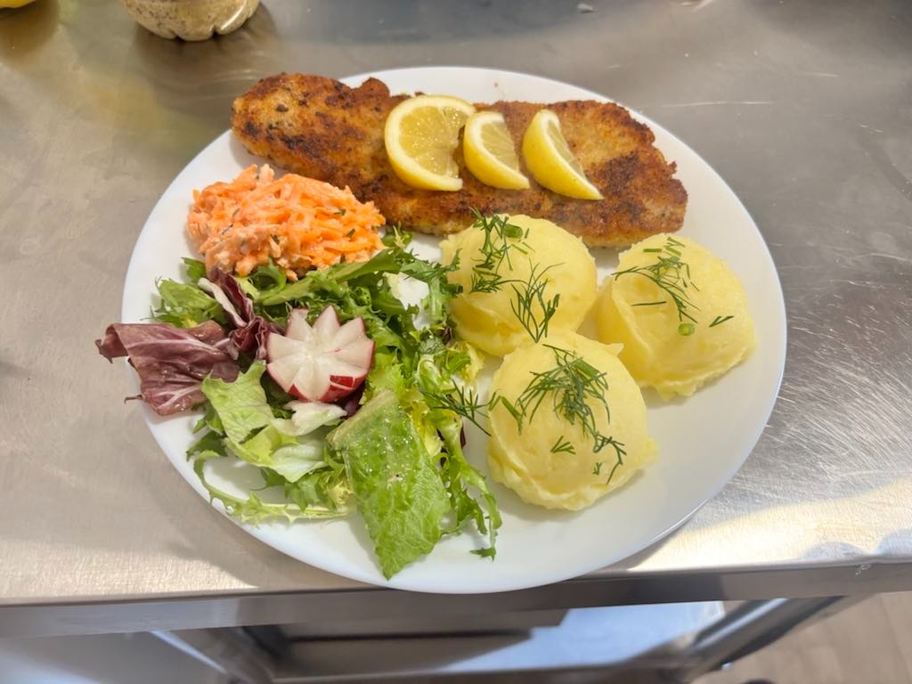 Zestaw obiadowy: kotlet schabowy z cytryną, ziemniaki z koperkiem i surówki na talerzu. Catering z Żyrardowa.