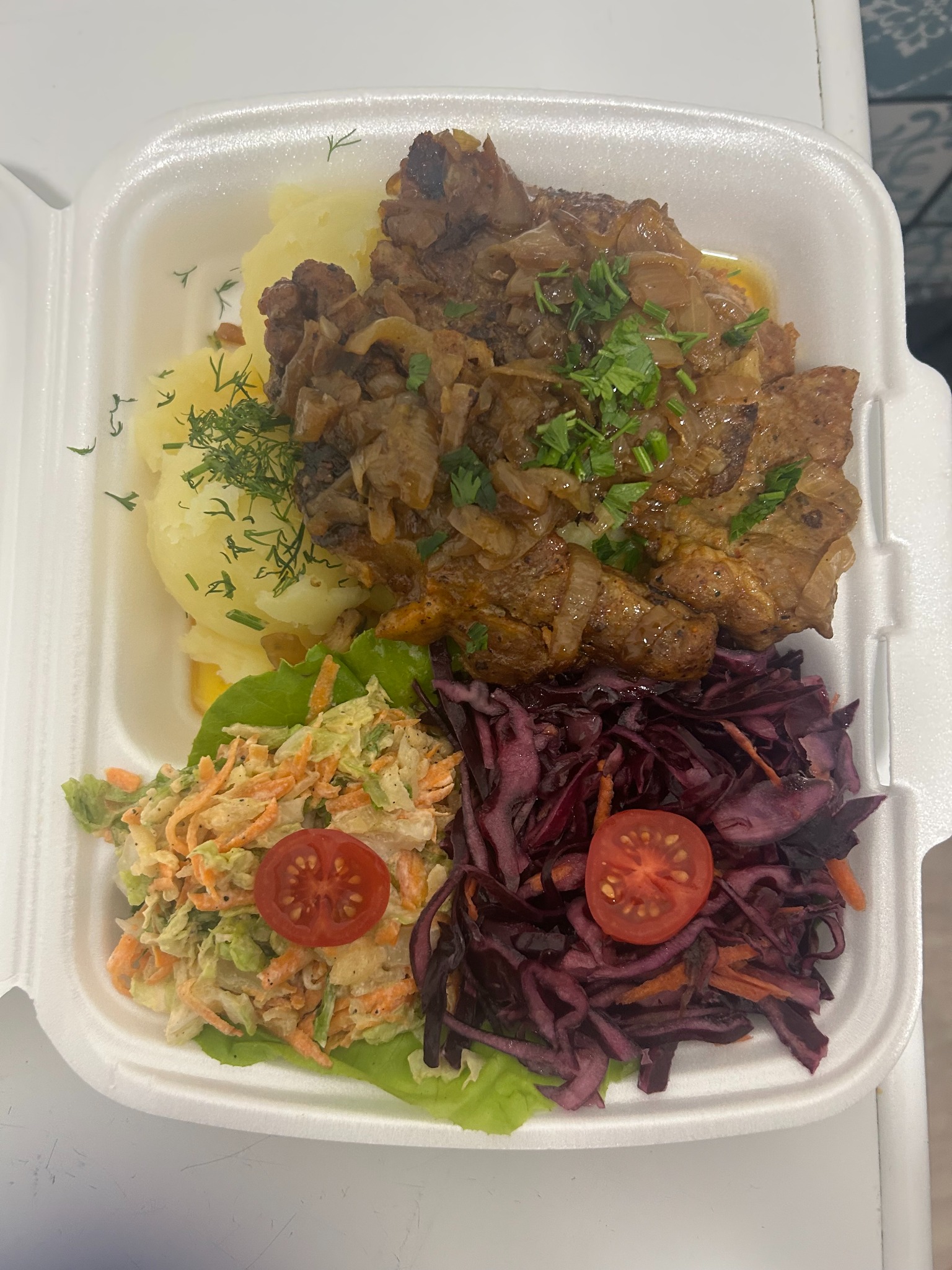 Lunchbox z obiadem: mięso duszone z cebulą, ziemniaki z koperkiem, surówka z czerwonej kapusty i marchewki, udekorowane pomidorkiem cherry.