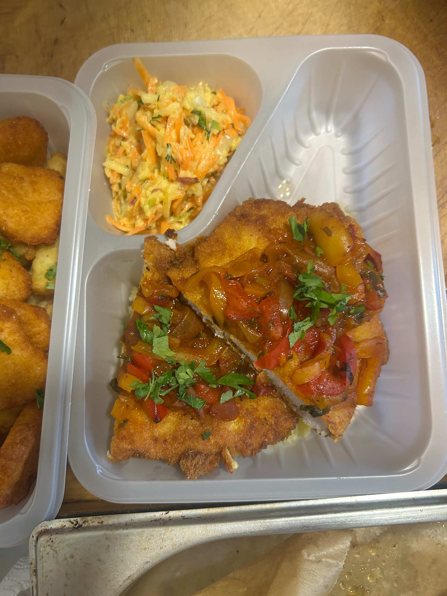 Lunchbox z kotletem w sosie paprykowym, sałatką colesław i krokietami ziemniaczanymi. Gotowy zestaw obiadowy w plastikowym pojemniku.