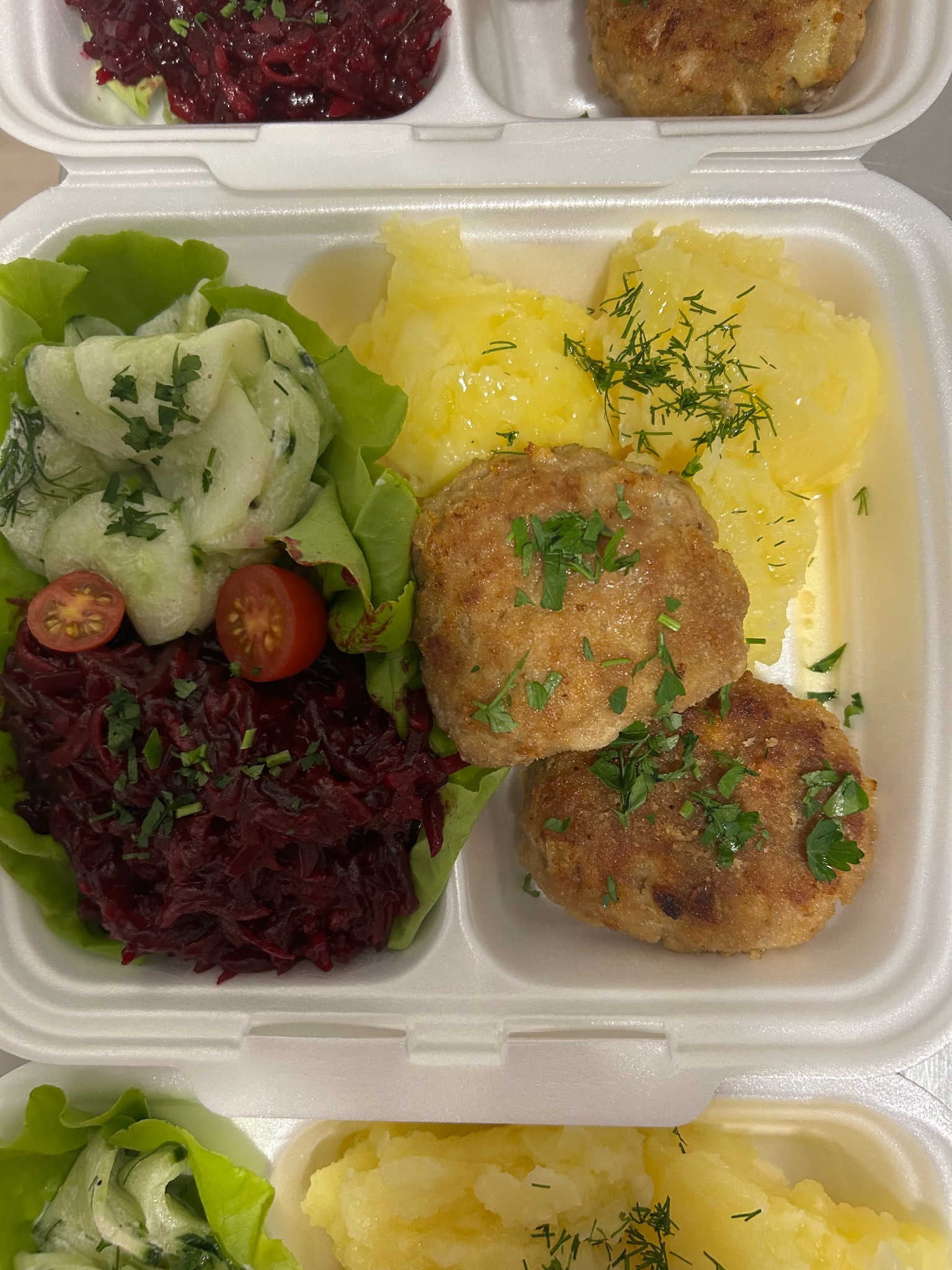 Lunchbox z zestawem obiadowym: kotlety mielone, ziemniaki z koperkiem, sałatka ogórkowa i buraczki. Danie gotowe do spożycia, zapakowane w pojemnik.