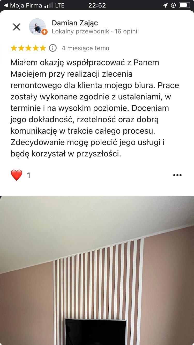 Opinia klienta o wykończeniu wnętrza biura: ściana w odcieniach różu z białymi, pionowymi listwami dekoracyjnymi. Widoczny fragment telewizora.