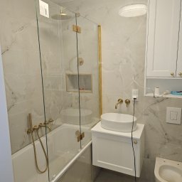 Łazienka z białego marmurku w połączeniu ze złotą armaturą podtynkową.