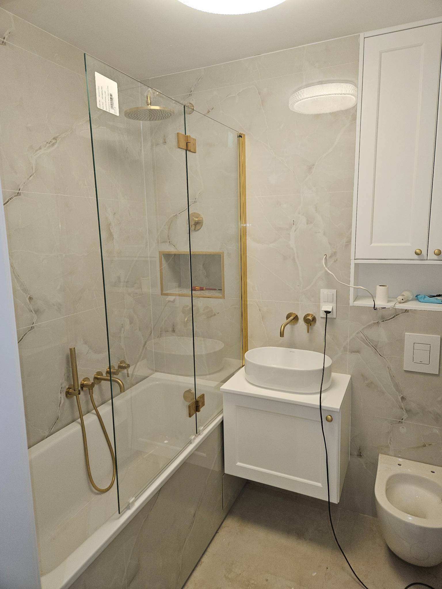 Łazienka z białego marmurku w połączeniu ze złotą armaturą podtynkową.