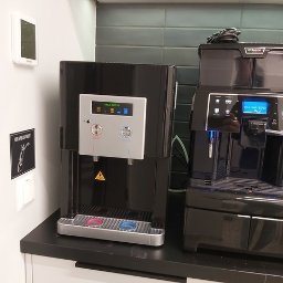 VENTONI SPÓŁKA Z OGRANICZONĄ ODPOWIEDZIALNOŚCIĄ - Czarny dystrybutor wody Mulhens obok ekspresu Saeco Aulika Evo na blacie. Dystrybutor z przyciskami ciepłej i zimnej wody, ekspres z wyświetlaczem i pojemnikiem na kawę.