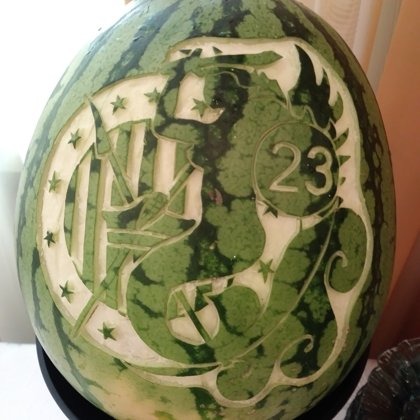 Ręcznie rzeźbiony arbuz z motywem rycerza, gwiazd i numeru 23. Dekoracja stołu na imprezę okolicznościową, ukazująca kunsztowne detale i unikalny charakter.