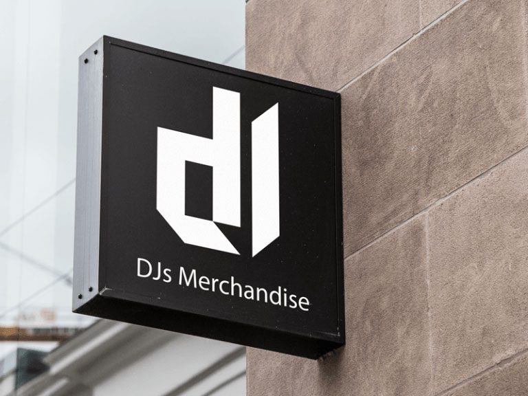 Kwadratowy szyld z logo 'dJ' w bieli na czarnym tle, z napisem 'DJs Merchandise', zamocowany na szarej, teksturowanej ścianie budynku. Minimalistyczny design.