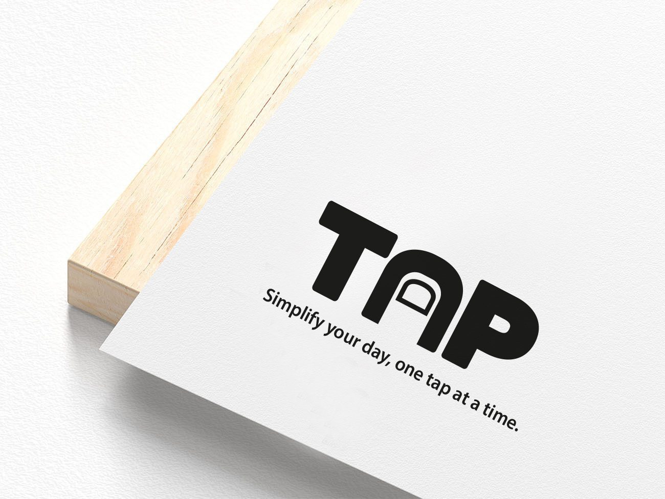 Minimalistyczny projekt logo 'TAP' z hasłem na białym tle, umieszczony na drewnianej ramce. Projekt graficzny z Głogowa.