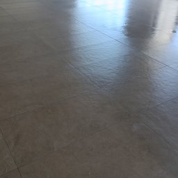 YRP.BUD - Beżowe, błyszczące płytki podłogowe ułożone w regularny wzór, z widocznym odbiciem światła z okien w tle. Minimalistyczny design, świeżo po realizacji.