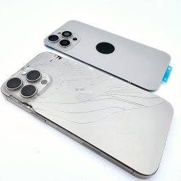 Klinika Szybek Naprawa Telefonów DAMIAN TOMASIK - Uszkodzony iPhone 13 Pro z pękniętą obudową leżący obok nowej, srebrnej obudowy. Widoczne trzy obiektywy aparatu. Białe tło.