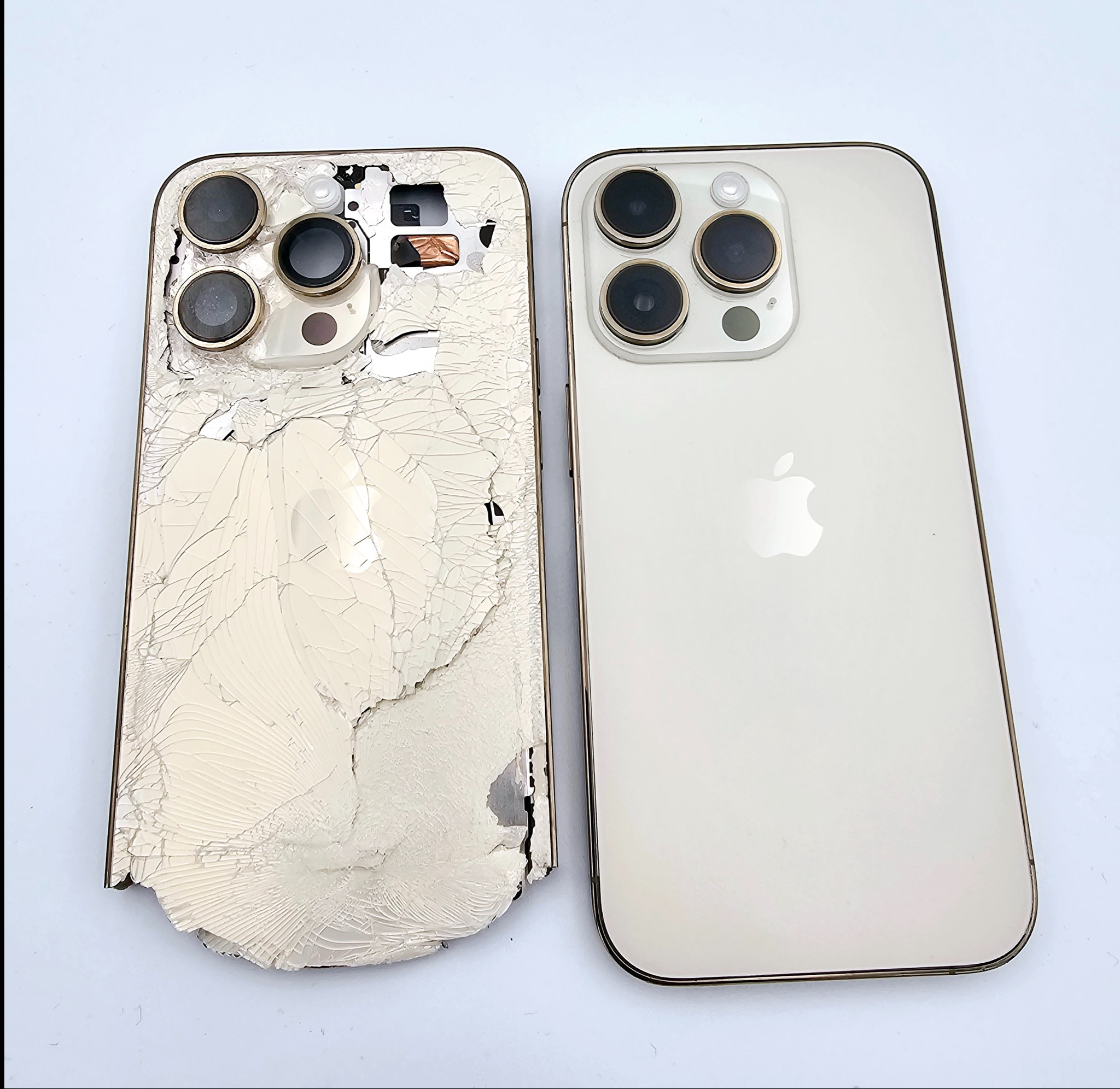 Uszkodzony iPhone 13 Pro obok sprawnego. Widoczne pęknięcia na obudowie i uszkodzone elementy wewnętrzne. Porównanie stanu przed i po naprawie.