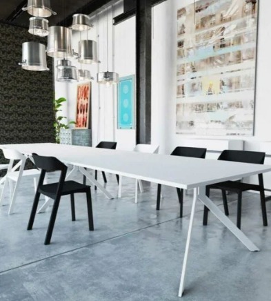 Nowoczesna sala konferencyjna z długim białym stołem, czarnymi krzesłami i designerskimi lampami z metalowych naczyń. Abstrakcyjny obraz na ścianie.