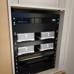 KRC TRADING GROUP SP. Z O.O. - Szafa rack z urządzeniami audio (Sonos) i wideo (Sky, Panasonic), uporządkowana instalacja w zabudowie meblowej, widoczne kable. Integracja systemów audio-wideo.