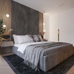 MR ATELIER SPÓŁKA Z OGRANICZONĄ ODPOWIEDZIALNOŚCIĄ - Tapicerowane łóżko w szarościach z wezgłowiem w geometryczne wzory. Obok szafka nocna z dekoracjami i wysoka szafa z ryflowanymi frontami. Całość w nowoczesnym stylu.