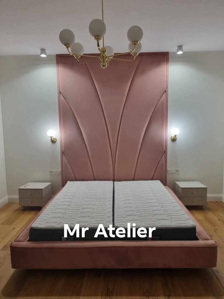 Różowe, tapicerowane łóżko z wysokim wezgłowiem o geometrycznym wzorze, z dwoma materacami i szafkami nocnymi w nowoczesnym wnętrzu z parkietem.