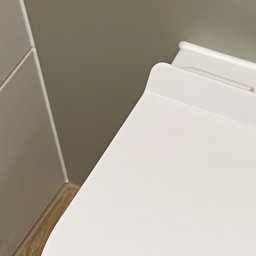 nowysilikon - Nowoczesna toaleta z deską wolnoopadającą, minimalistyczny design, jasne kolory, drewnopodobna podłoga, szara ściana. Detal wykończenia łazienki.