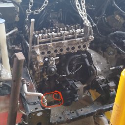 Zarasprint LTD - Silnik samochodowy zawieszony na łańcuchu w warsztacie, widoczne elementy konstrukcyjne pojazdu i narzędzia. Detal: czerwone okręgi na silniku.