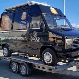 Zarasprint LTD - Czarna furgonetka z reklamą 'Mr. Potato' na lawecie, widok z boku. Tablica rejestracyjna widoczna. Błękitne niebo w tle. Chromowane felgi.