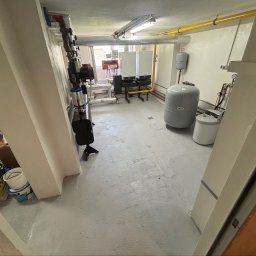 KrysTech - Kompletna instalacja grzewcza z dwoma białymi piecami gazowymi Viessmann, dużym szarym zbiornikiem Reflex, rurami grzewczymi i żółtymi gazowymi w jasnej kotłowni.
