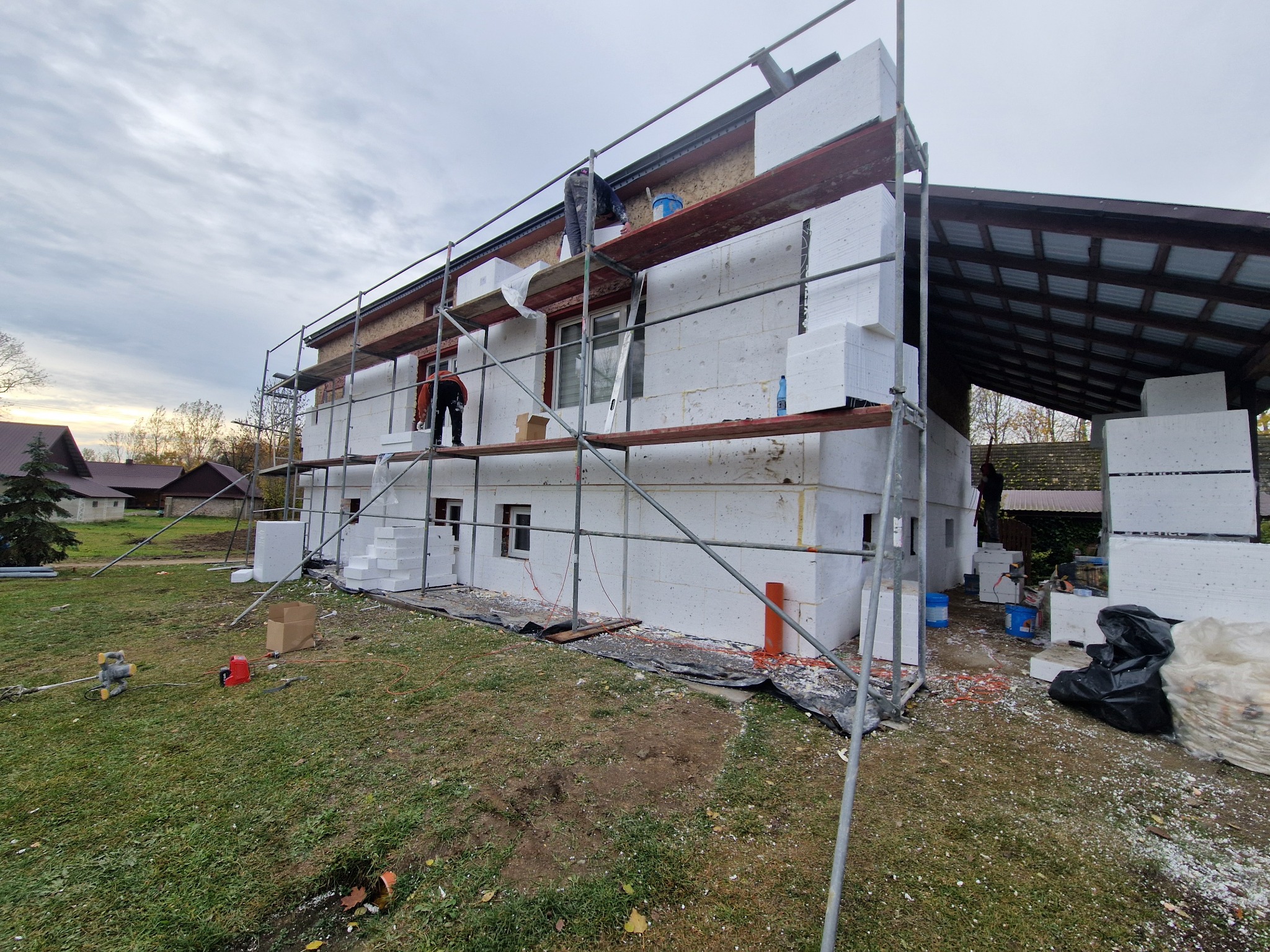 Ocieplanie elewacji domu jednorodzinnego styropianem, widoczne rusztowania i pracownicy. Prace w toku, Białystok.