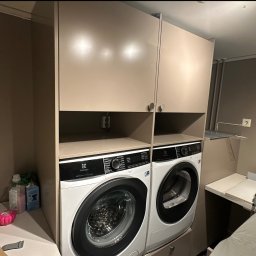 SERWIS DOMOWY - Dwie pralki Electrolux w zabudowie meblowej z szafkami, widoczne gniazdko elektryczne. Ustawienie pionowe, oszczędność miejsca w małej łazience.