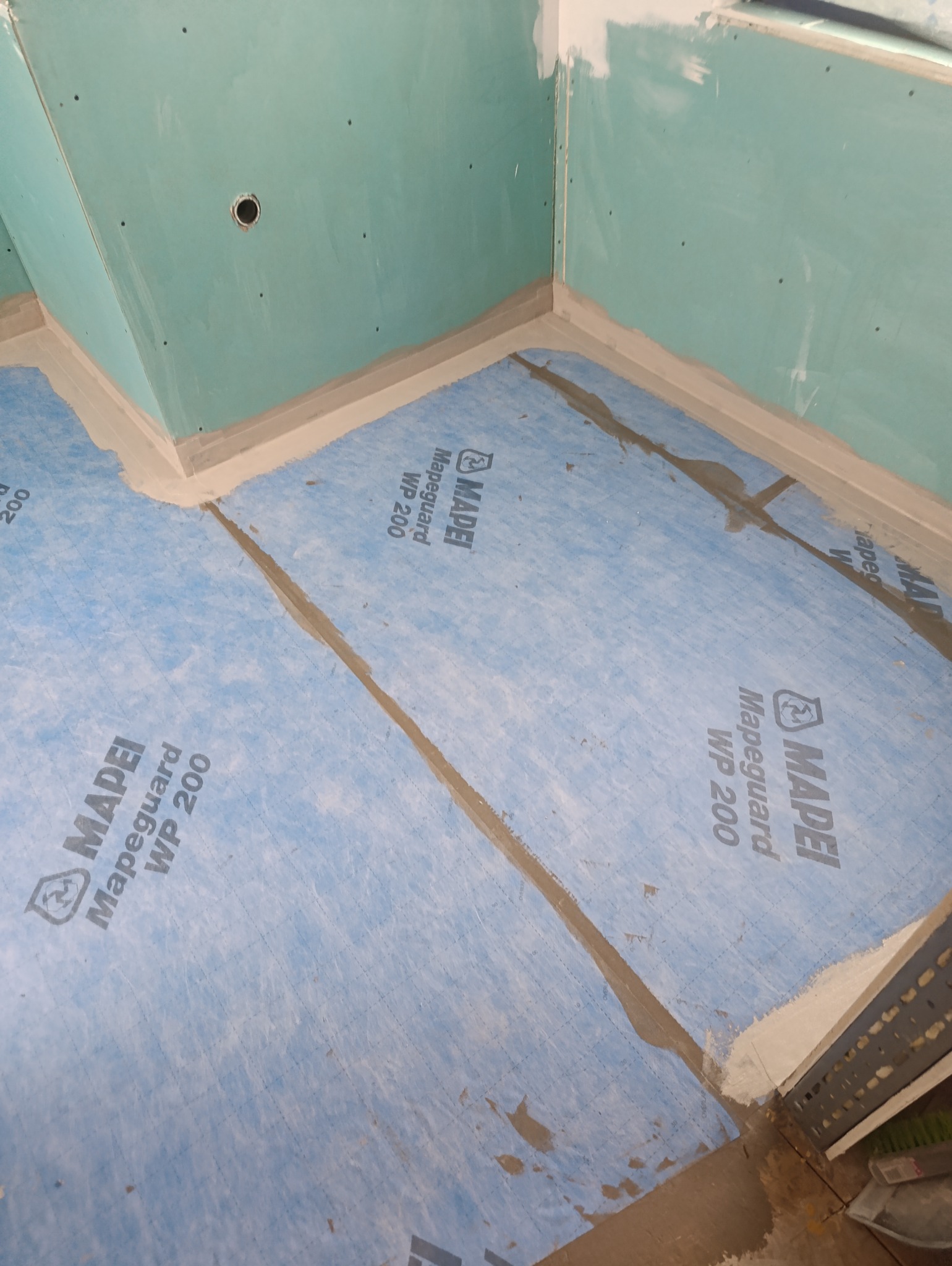 Hydroizolacja podłoża w łazience, membrana Mapeguard WP 200 na podłodze i ścianach, przygotowanie do dalszych prac wykończeniowych.