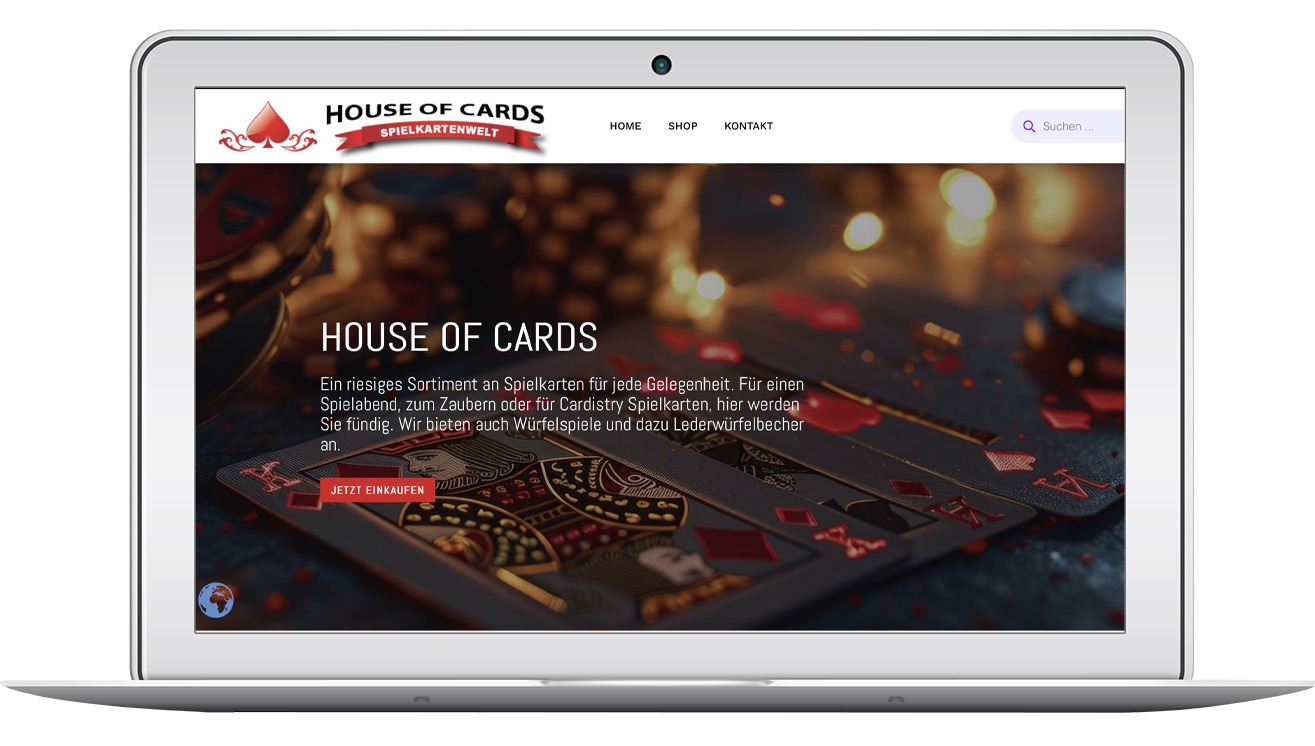 Laptop prezentuje stronę internetową 'House of Cards' z motywem kart do gry, ciemnym tłem i czerwonymi akcentami. Widoczny pasek nawigacyjny i tekst w języku niemieckim.