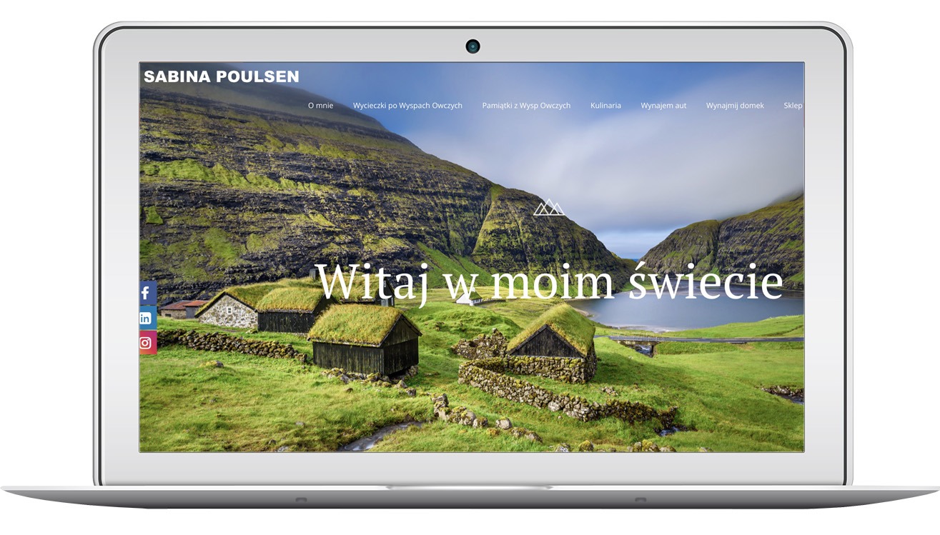 Laptop wyświetla stronę internetową sabinapoulsen.com z krajobrazem Wysp Owczych i napisem 'Witaj w moim świecie'. Widoczne menu strony i ikony mediów społecznościowych.