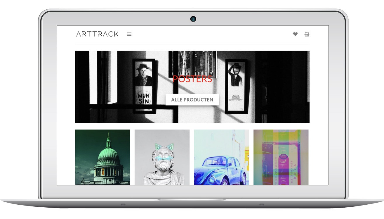 Ekran laptopa prezentuje stronę sklepu internetowego Arttrack-shop.com z grafikami i plakatami. Widoczne menu, ikony koszyka i serca, oraz przykładowe produkty.
