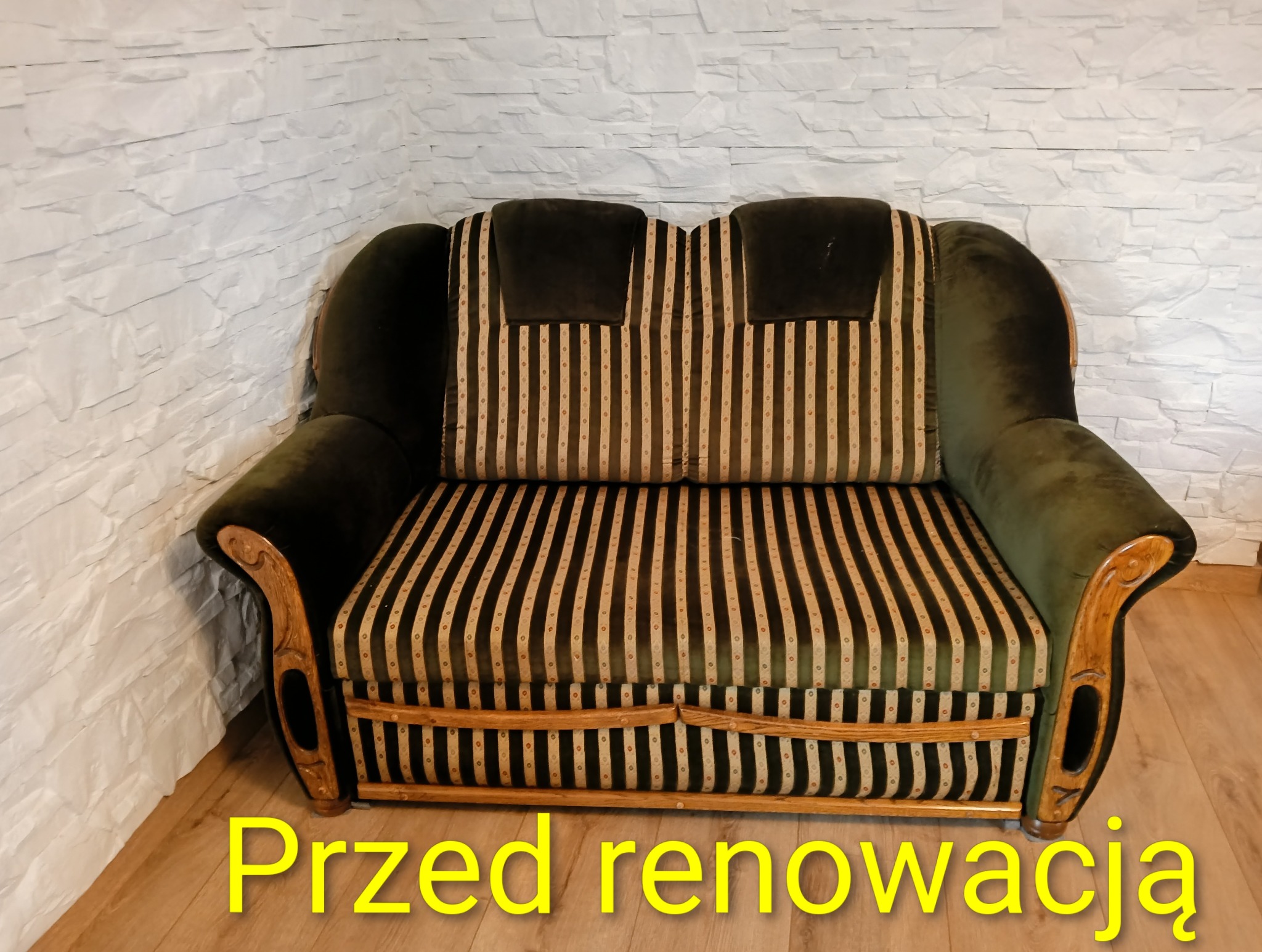 Antyczny, zielony fotel z drewnianymi zdobieniami i wzorzystą tapicerką w pionowe pasy, sfotografowany przed renowacją na tle białej ściany z imitacją kamienia.