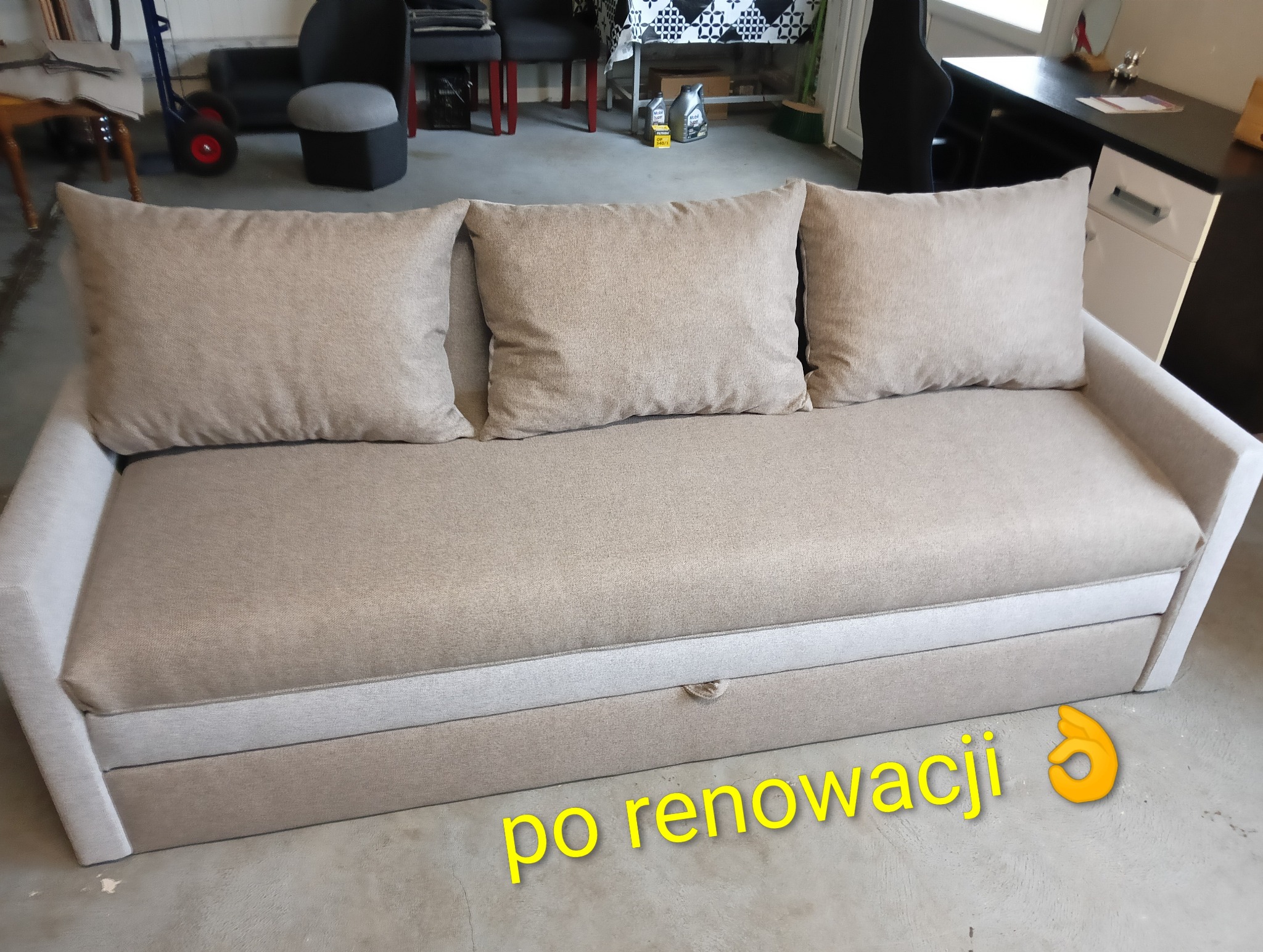Jasna sofa z trzema poduszkami po renowacji, widoczna na tle garażu. Sofa ma schowek. Na podłodze widoczny napis 'po renowacji'.