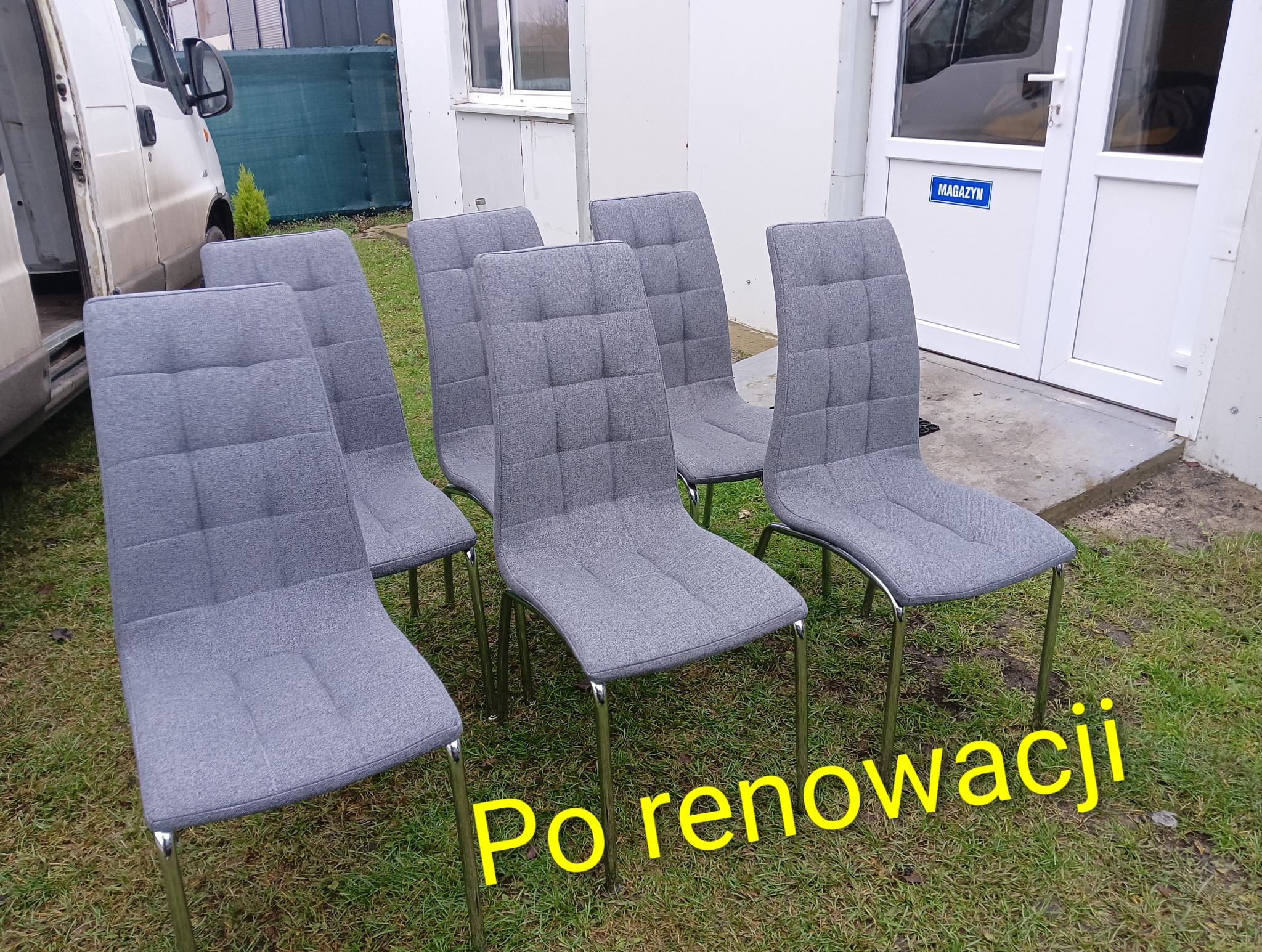 Sześć szarych krzeseł tapicerowanych z kwadratowym wzorem, ustawionych na trawie przed budynkiem magazynowym i busem. Napis 'Po renowacji'.