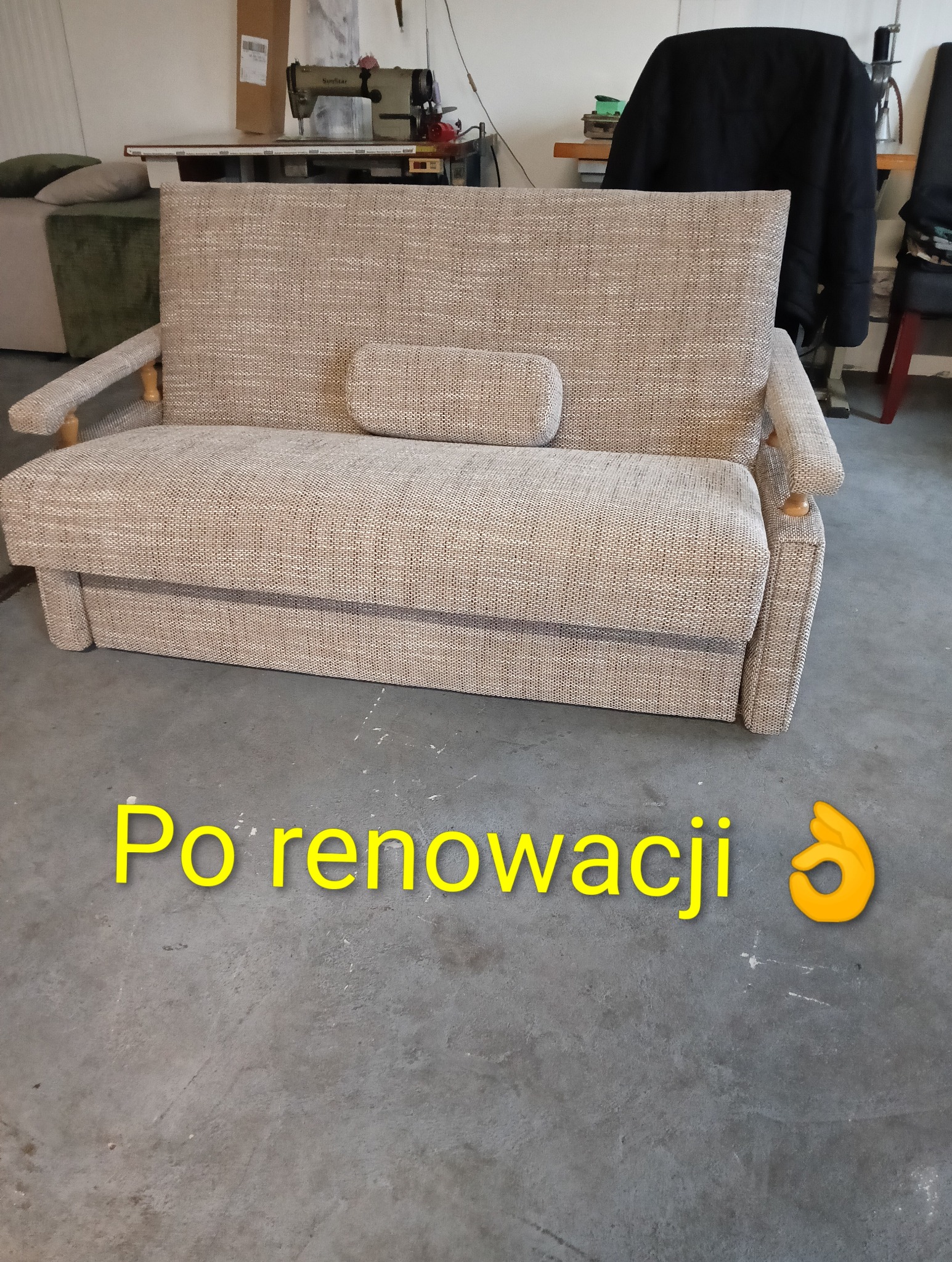 Odnowiona sofa z beżową tapicerką w Sadkach. Widoczna maszyna do szycia w tle. Renowacja mebli tapicerowanych z dbałością o detale.