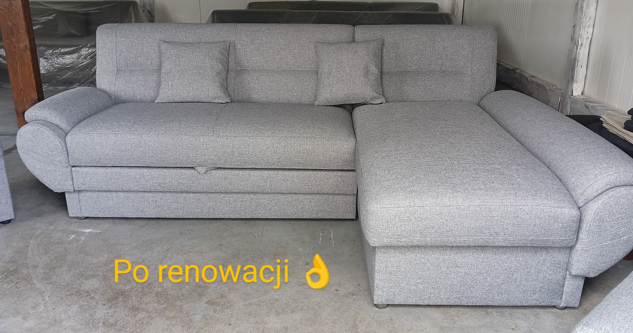 Szary narożnik z funkcją spania i dwoma poduszkami, po renowacji, widoczny z przodu, z bliska. Tapicerka o jednolitej fakturze, minimalistyczny design.