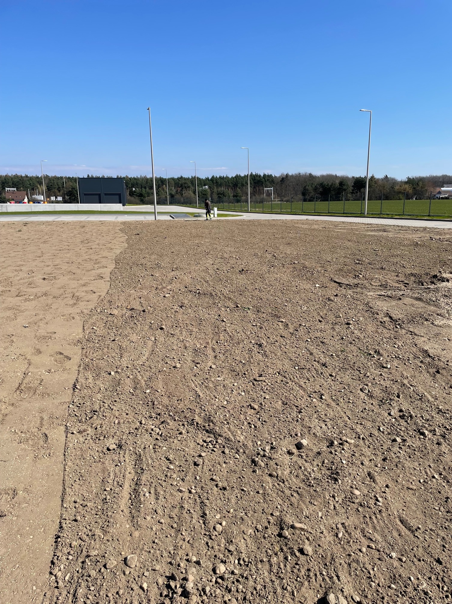 Wysiew trawy bez mikroniwelacji na terenach wokół hali przemysłowej.