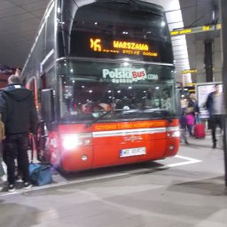 PolskiBus - Czerwony autobus Polski Bus na dworcu, z wyświetlonym numerem linii 16 i kierunkiem Warszawa. Widoczni pasażerowie z bagażami i fragment peronu.