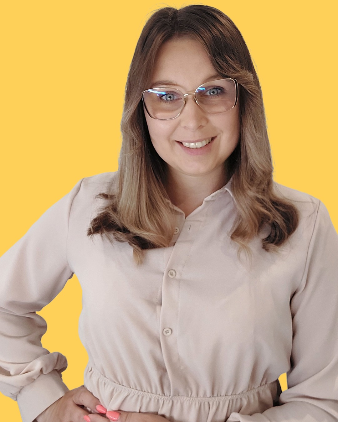 Uśmiechnięta kobieta w okularach, z rękami na biodrach, na żółtym tle. Profesjonalny wizerunek specjalisty z Brzózy, budzący zaufanie.