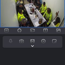 VX Adrian Kurowski - Podgląd z kamery monitoringu: grupa osób w odblaskowych kamizelkach siedzi przy stole w pomieszczeniu. Widok z aplikacji mobilnej, data i godzina w prawym górnym rogu.