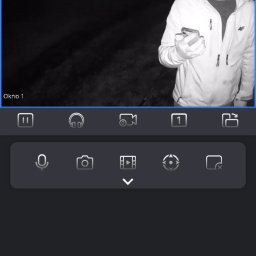 VX Adrian Kurowski - Podgląd z kamery monitoringu nocą: mężczyzna w kurtce 4F sprawdza obraz na smartfonie. Widoczny interfejs aplikacji z opcjami nagrywania i podglądu.