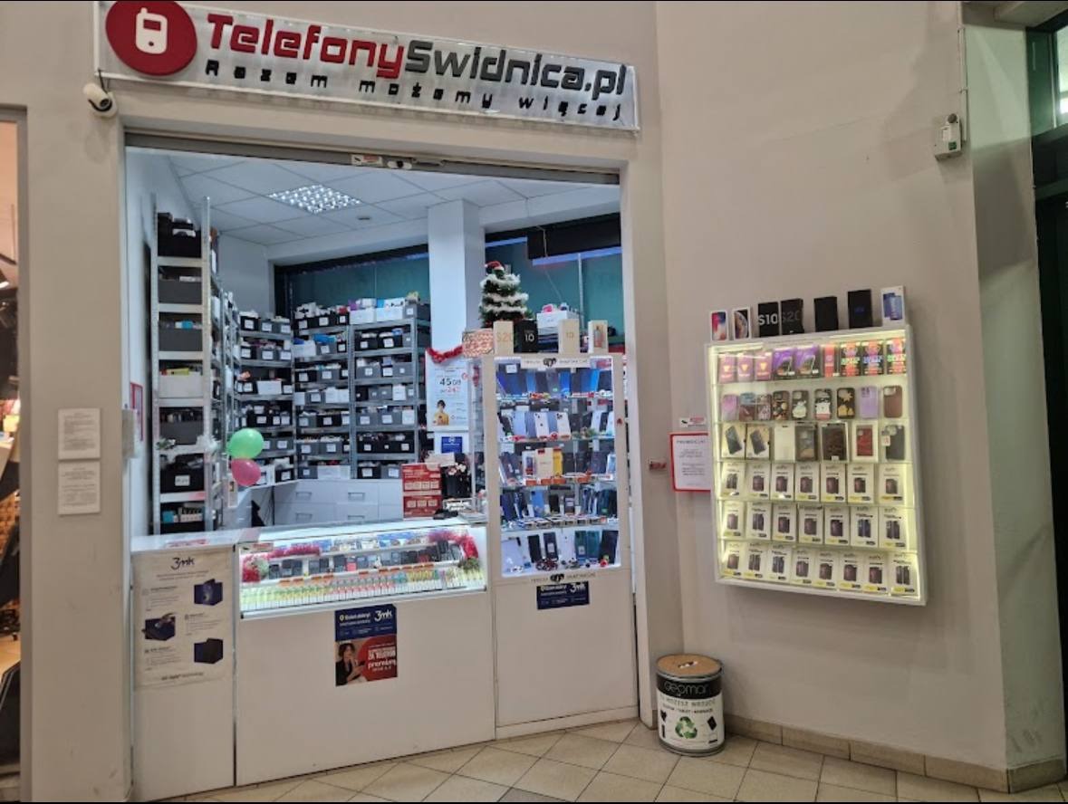 Wnętrze punktu serwisowego telefonów z logo 'TelefonySwidnica.pl', ekspozycją akcesoriów i telefonów. W tle widoczna choinka.